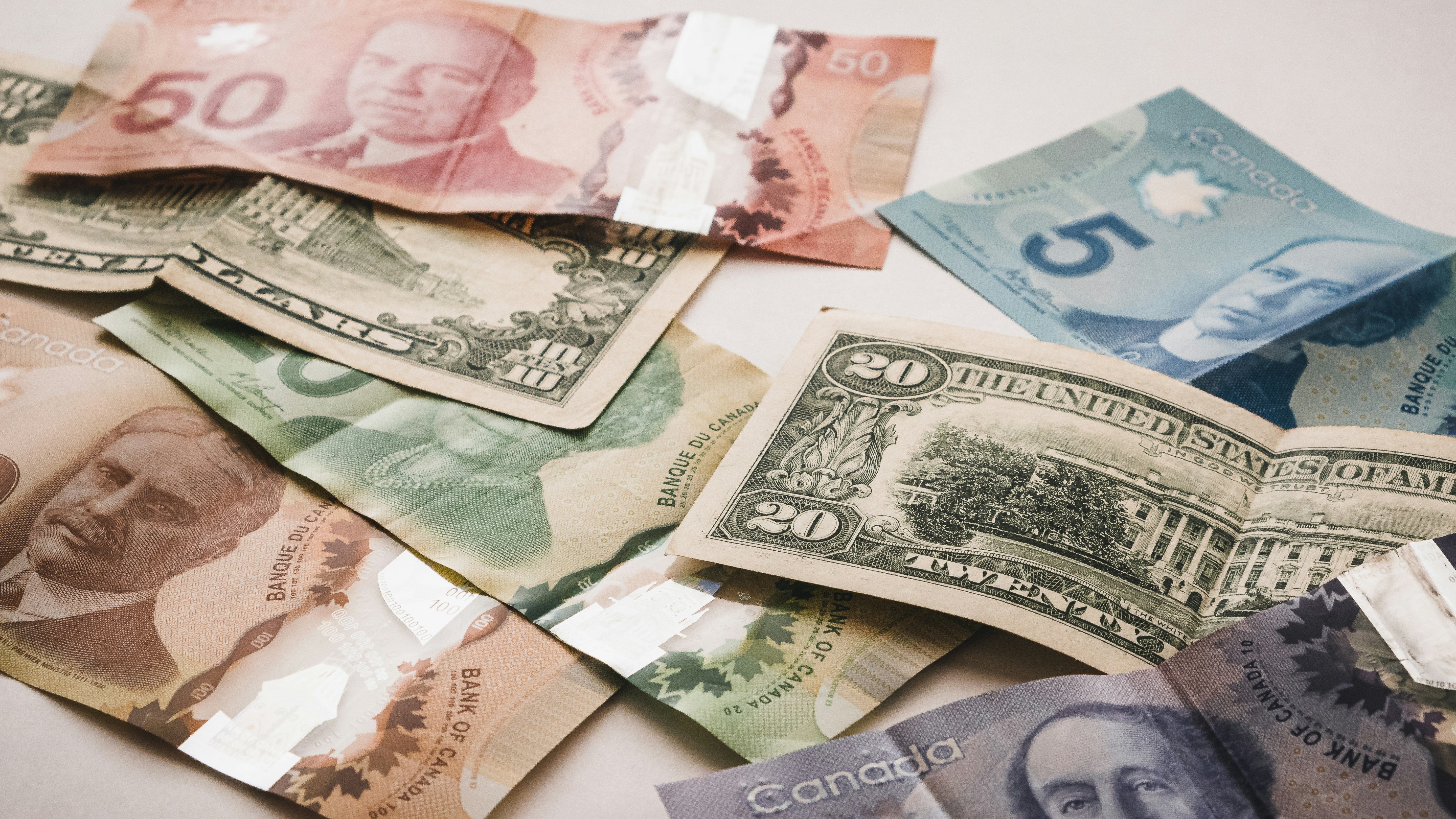 Canadian and American money scattered on a white background