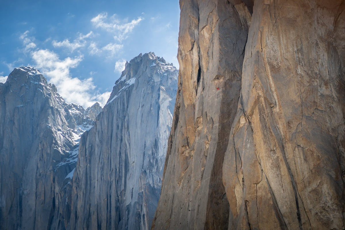 Photo from Flow, of Anna Šebestíková  by Standa Mitac. The photo features a stunning, massive rock face with more blue-toned mountains in the distance behind the main face. The subject, Anna Šebestíková , is very small on the first closest rock face.